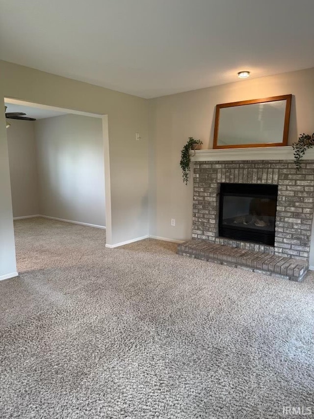 unfurnished living room with carpet floors, baseboards, and a fireplace