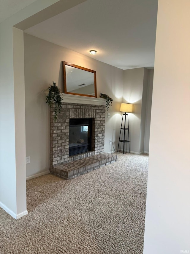unfurnished living room with carpet floors, baseboards, and a brick fireplace