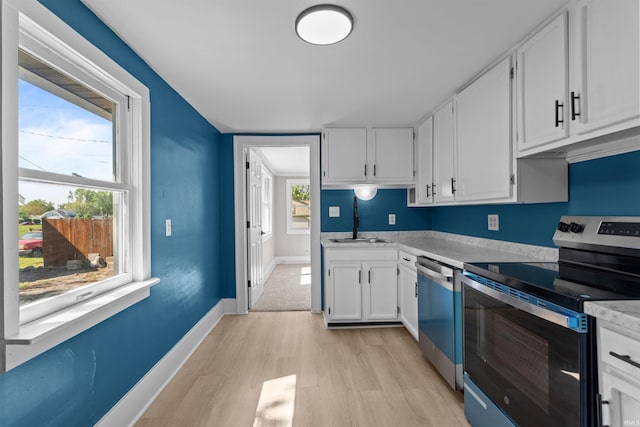 1508 E Hoffer St, Kokomo, IN 46902 - kitchen with stainless steel appliances, light wood-style floors, a sink, light countertops, and white cabinets