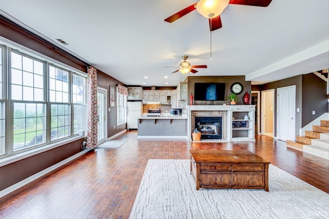 living room with ceiling fan, healthy amount of natural light, light wood-style flooring, and baseboards