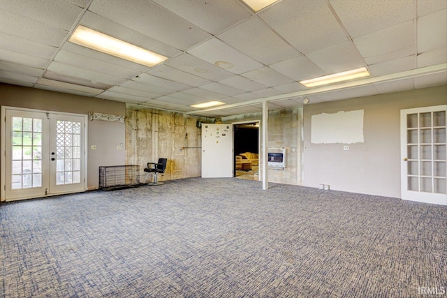 basement with carpet, a drop ceiling, heating unit, and french doors