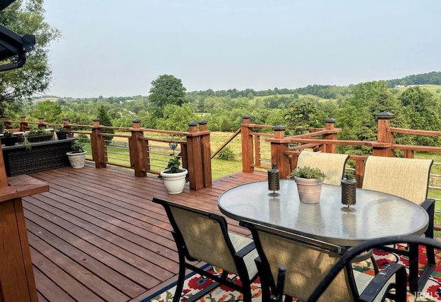 wooden terrace with outdoor dining area and a forest view