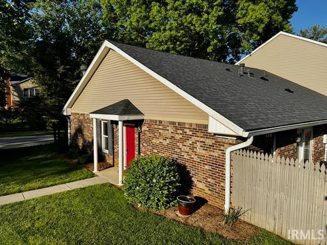 view of front facade featuring brick siding and roof with shingles