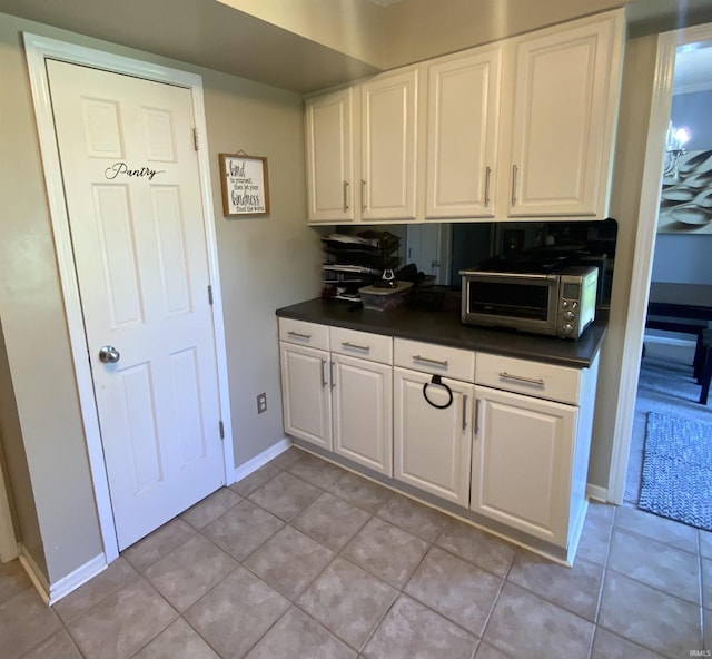 1108 Silver Springs Ct, Fort Wayne, IN 46825 - kitchen featuring white cabinetry, dark countertops, light tile patterned flooring, and baseboards