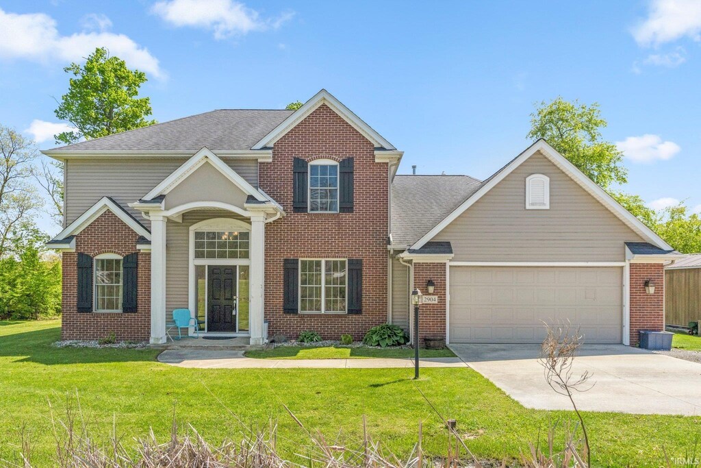 2904 Union Chapel Rd, Fort Wayne, IN 46845 - traditional-style home featuring concrete driveway, a garage, a front lawn, and brick siding