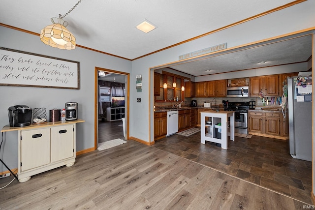 47 E Center St, Williamsport, IN 47993 - kitchen featuring stainless steel appliances, ornamental molding, brown cabinetry, wood finished floors, and baseboards