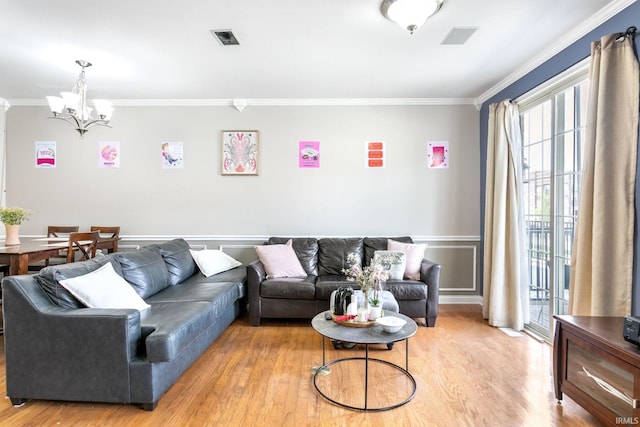 living room featuring crown molding, a chandelier, light wood-type flooring, and wainscoting