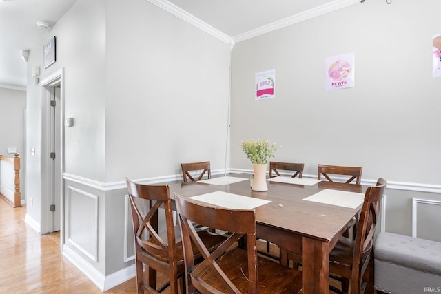 dining room with crown molding, light wood finished floors, and baseboards