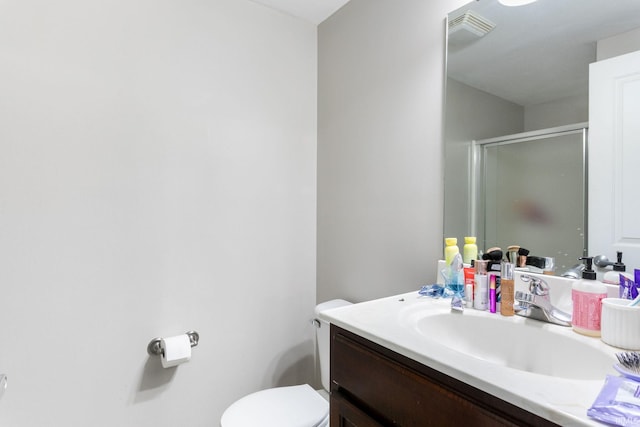bathroom with vanity, a shower stall, and toilet