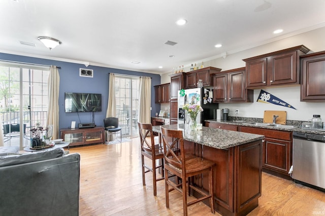 kitchen with dishwasher, refrigerator with ice dispenser, a sink, a kitchen breakfast bar, and light wood-type flooring