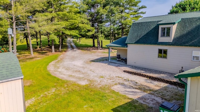 view of side of property with roof with shingles and a yard
