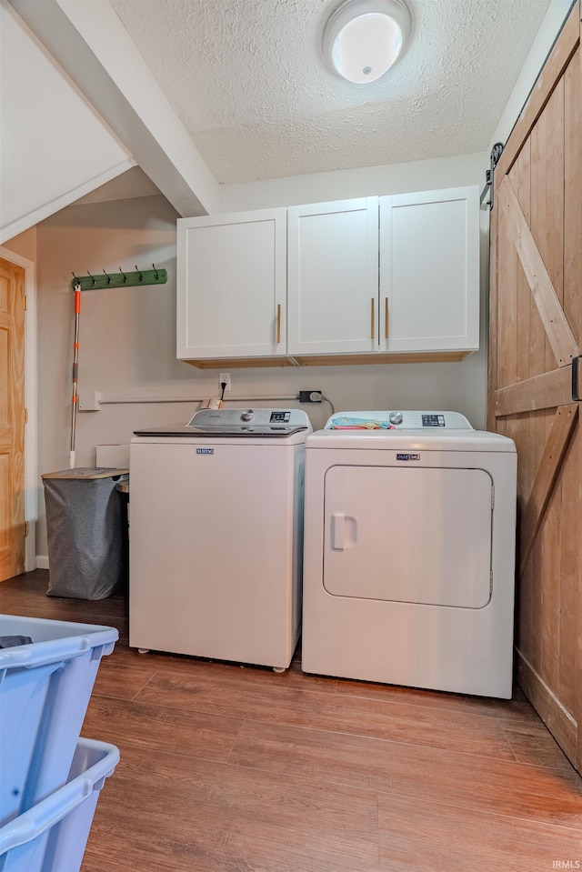 laundry room featuring cabinet space, separate washer and dryer, a textured ceiling, light wood-style flooring, and baseboards