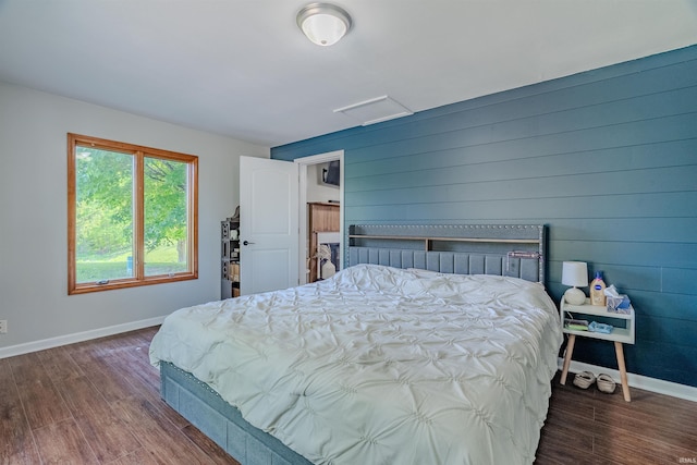 bedroom with wood finished floors, baseboards, and attic access