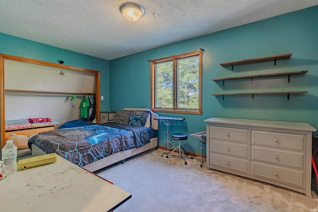 bedroom with a textured ceiling, light colored carpet, and baseboards