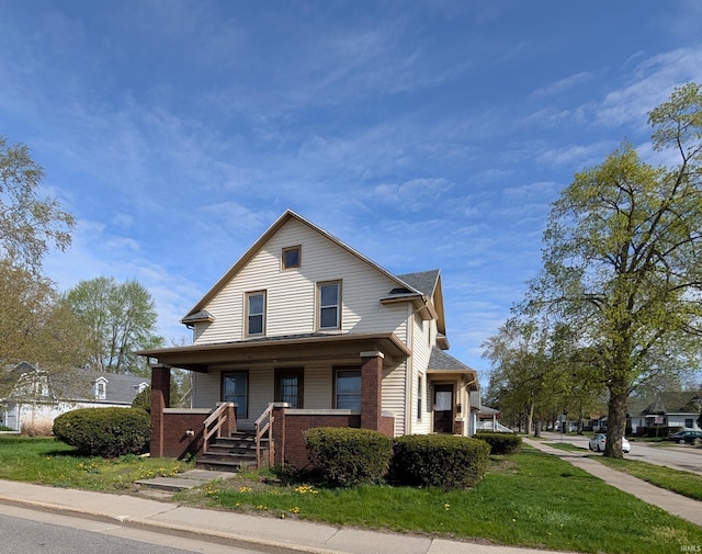 view of front of property featuring brick siding, a porch, and a front lawn