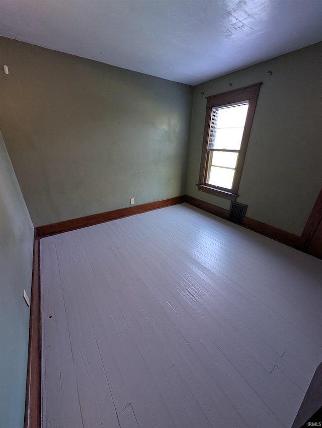 spare room with wood finished floors and baseboards