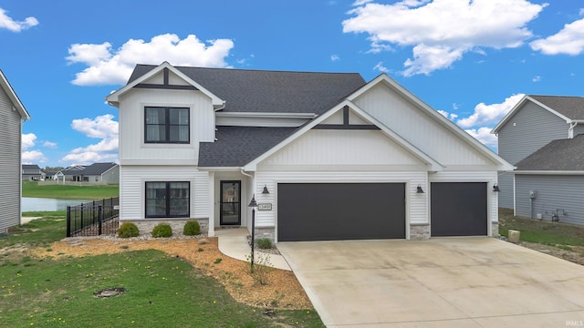 modern inspired farmhouse featuring stone siding, a garage, driveway, a shingled roof, and a water view