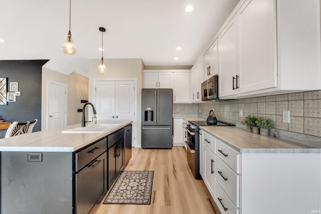 kitchen featuring appliances with stainless steel finishes, a sink, light countertops, and white cabinetry