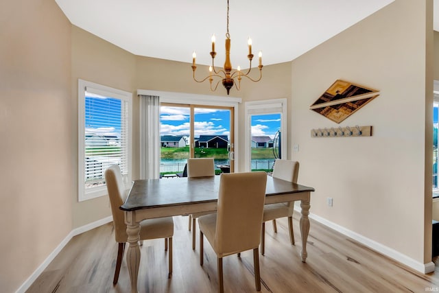 dining space with a chandelier, light wood-style floors, and baseboards