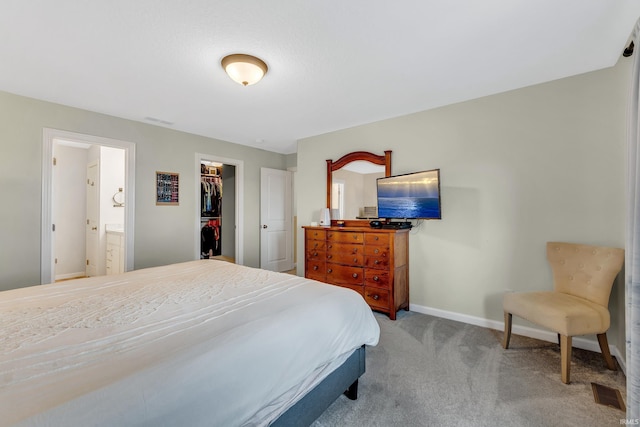 carpeted bedroom featuring baseboards, ensuite bathroom, a spacious closet, and a closet