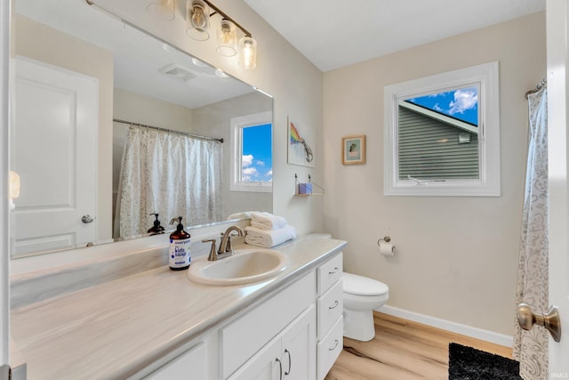 bathroom featuring wood finished floors, baseboards, toilet, and vanity
