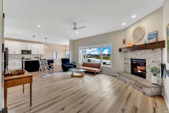 living room with a stone fireplace, light wood-style flooring, ceiling fan, recessed lighting, and baseboards