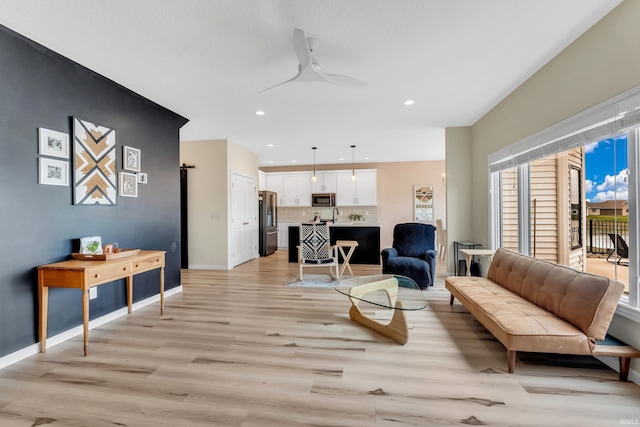 living room with light wood-type flooring, baseboards, recessed lighting, and a ceiling fan