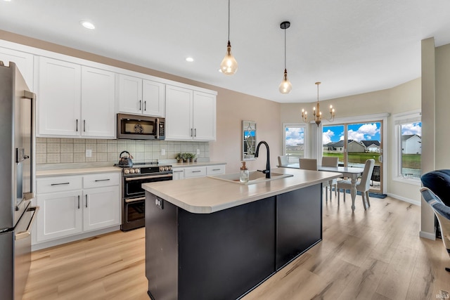 kitchen featuring appliances with stainless steel finishes, a sink, light wood-type flooring, a chandelier, and recessed lighting