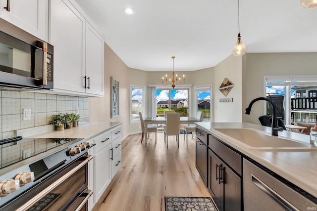 kitchen featuring stainless steel appliances, a sink, a chandelier, white cabinets, and recessed lighting