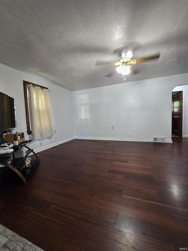 304 N Main St, South Whitley, IN 46787 - unfurnished living room featuring a ceiling fan, wood finished floors, arched walkways, a textured ceiling, and baseboards