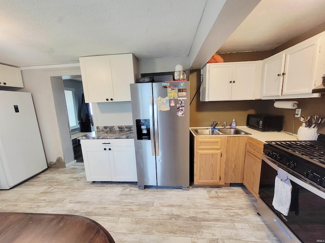109 N Martin St, Ligonier, IN 46767 - kitchen with stainless steel appliances, light wood-style flooring, white cabinets, and a textured ceiling