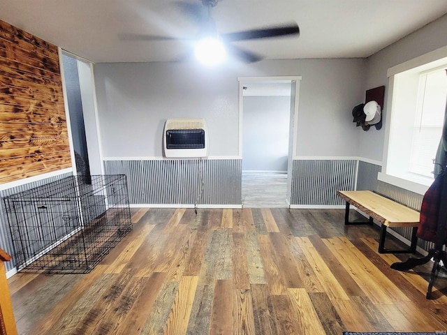 109 N Martin St, Ligonier, IN 46767 - unfurnished living room featuring heating unit, ceiling fan, wood finished floors, and a wainscoted wall