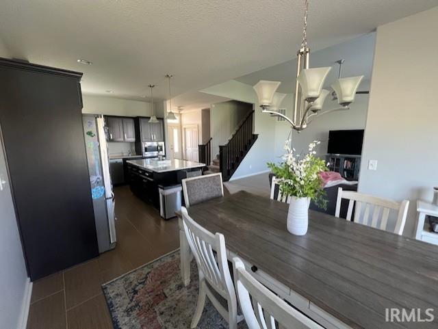 dining area featuring stairs, a chandelier, and baseboards