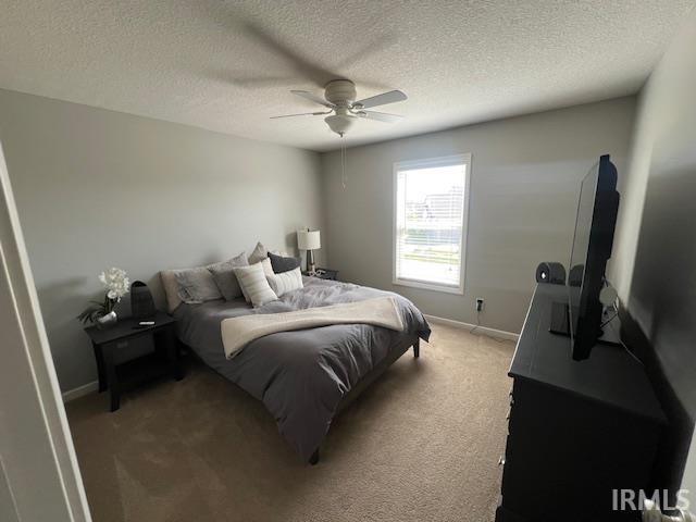 bedroom featuring baseboards, light carpet, a textured ceiling, and ceiling fan