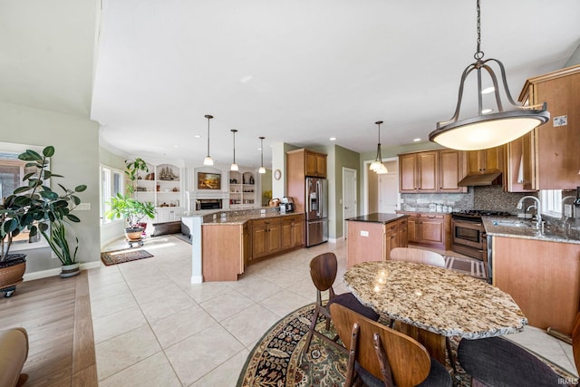 51025 Bellcrest Cir, Granger, IN 46530 - kitchen featuring appliances with stainless steel finishes, under cabinet range hood, a peninsula, brown cabinetry, and baseboards