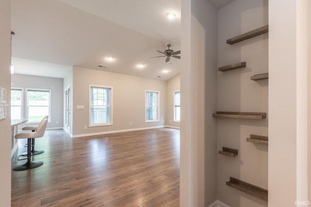 unfurnished living room featuring dark wood finished floors, a ceiling fan, baseboards, recessed lighting, and vaulted ceiling