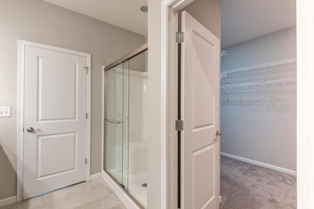 full bathroom featuring a shower stall, baseboards, and a spacious closet