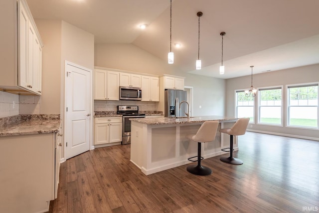 kitchen featuring stainless steel appliances, backsplash, dark wood finished floors, white cabinets, and an island with sink