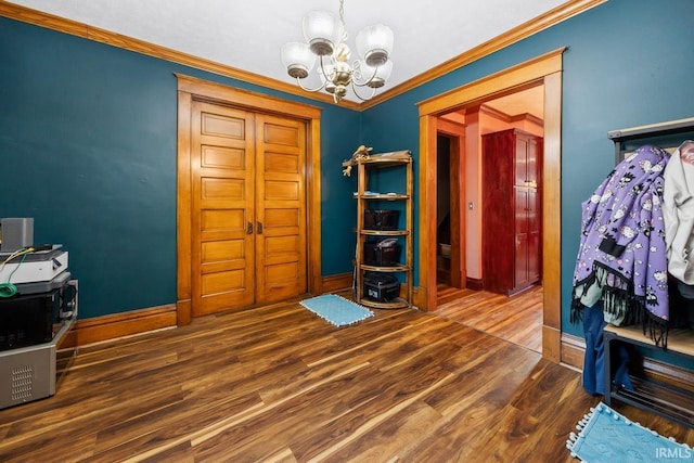 interior space featuring a chandelier, wood finished floors, baseboards, and ornamental molding
