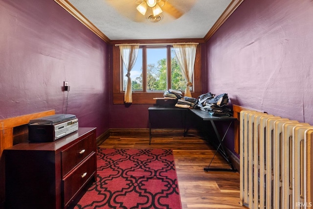 office space with radiator heating unit, crown molding, wood finished floors, ceiling fan, and a textured ceiling