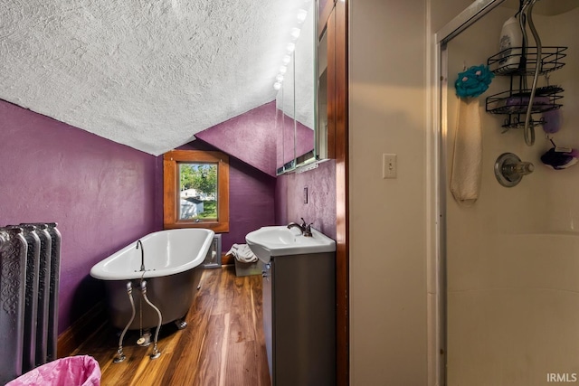 bathroom with a textured ceiling, radiator, wood finished floors, lofted ceiling, and vanity