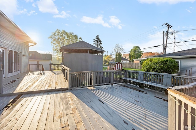 deck with a storage shed, an outbuilding, and fence