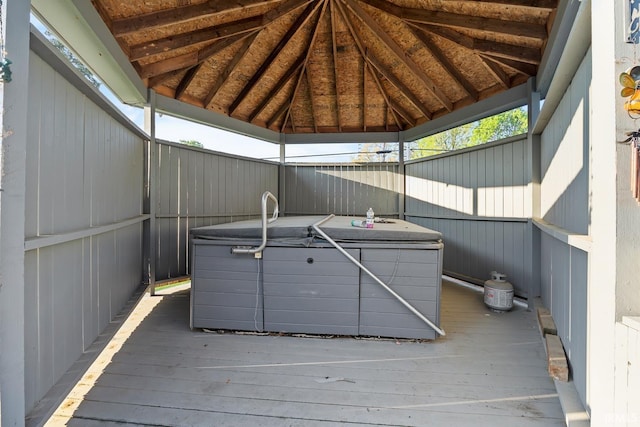 wooden deck with a hot tub, a gazebo, and fence