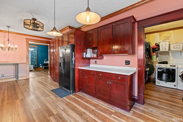 kitchen with black refrigerator with ice dispenser, washer and clothes dryer, dark brown cabinets, pendant lighting, and light wood-style flooring