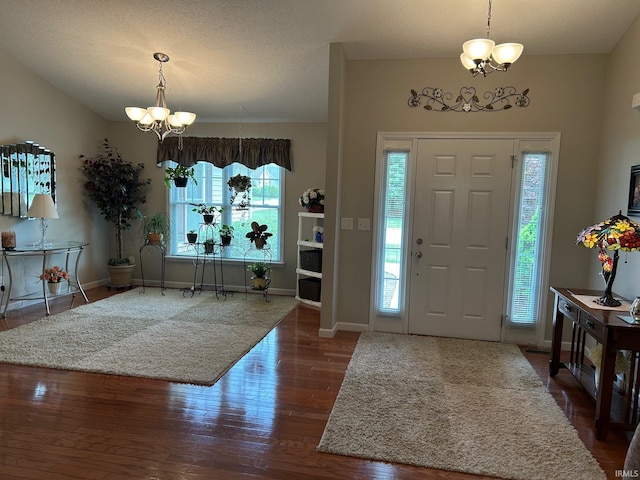 foyer entrance featuring a chandelier, wood finished floors, and baseboards