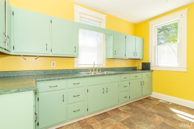 kitchen featuring a sink, baseboards, and stone finish flooring