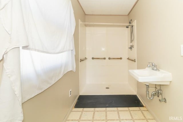 bathroom with tile patterned floors, a shower, baseboards, and a sink