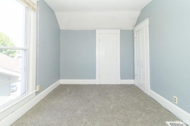 carpeted empty room with lofted ceiling and baseboards