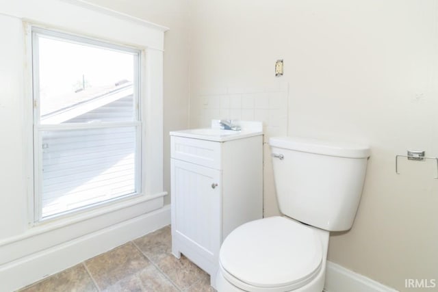 half bathroom with healthy amount of natural light, toilet, and vanity