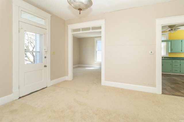 foyer with light carpet, baseboards, and a ceiling fan